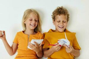 portret van schattig liggen Aan de verdieping met blocnotes en potloden geïsoleerd achtergrond ongewijzigd foto