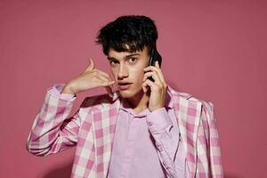 een jong Mens met een telefoon in hand- roze blazer mode elegant stijl geïsoleerd achtergrond ongewijzigd foto