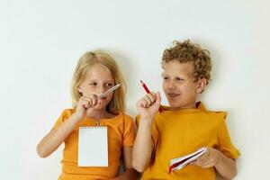 portret van schattig liggen Aan de verdieping met blocnotes en potloden geïsoleerd achtergrond ongewijzigd foto