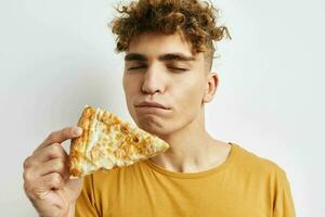 knap jong Mens in een geel t-shirt aan het eten pizza levensstijl ongewijzigd foto