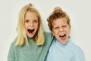 schattig elegant kinderen in veelkleurig truien poseren voor pret licht achtergrond foto