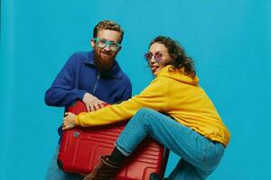 vrouw en Mens glimlach koffers in hand- met geel en rood koffer glimlach plezier, Aan blauw achtergrond, inpakken voor een reis, familie vakantie reis. foto