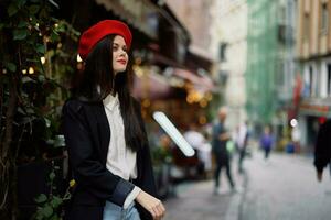 vrouw glimlach mode model- wandelingen Aan de straat in de stad centrum tussen de menigte in een jasje en rood baret en jeans, filmische Frans mode stijl kleding, reizen naar Istanbul foto