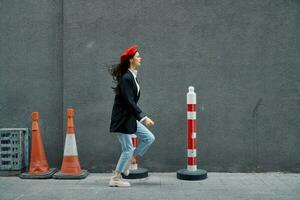 mode vrouw rennen naar beneden de straat in voorkant van de stad toerist in elegant kleren met rood lippen en rood baret, reis, filmische kleur, retro wijnoogst stijl, laat naar werk, rennen. foto