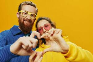 Mens en vrouw paar glimlachen vrolijk en scheef met bril, Aan geel achtergrond, symbolen tekens en hand- gebaren, familie schieten, pasgetrouwden. foto