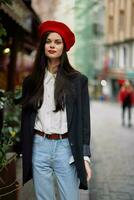 vrouw glimlach mode model- wandelingen Aan de straat in de stad centrum tussen de menigte in een jasje en rood baret en jeans, filmische Frans mode stijl kleding, reizen naar Istanbul voorjaar foto