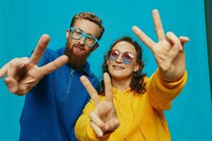 een vrouw en een Mens pret paar aanzwengelen en tonen tekens met hun handen glimlachen vrolijk, Aan een blauw achtergrond, de concept van een echt verhouding in een familie. foto