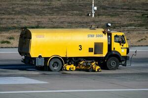 luchthaven landingsbaan schoonmaak. vliegveld beton en asfalt oppervlakte schoner. sneeuwploeg. sneeuw en aarde verwijdering trekker voertuig. foto