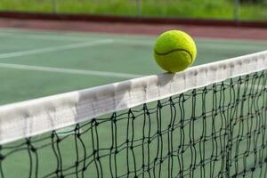 dichtbij omhoog van tennis bal clips de top van de netto. tennis bal raken de netto en gaat naar de andere kant. foto