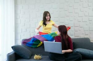 lgbt paren gebruik regenboog vlaggen naar Hoes hun geliefde degenen. werken Aan de sofa in de leven kamer van de huis foto