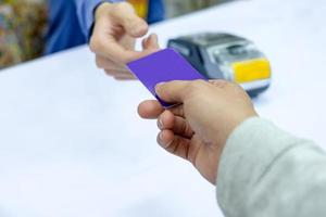 met de hand betalende creditcard op betaalterminal met personeelskassier foto