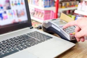 handpers met het vegen van creditcard op ternimal en met behulp van laptopbetaling online winkelen