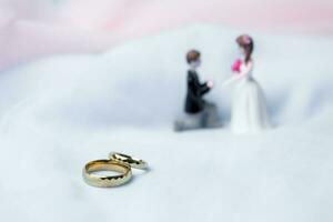 gouden bruiloft ringen voor verloving. huwelijk gouden ringen met wit, roze linten achtergrond. ringen Aan de wit en rood roos. de huwelijk ringen is de symbool van traditioneel bruiloft van paar- liefhebbers. foto