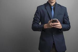 close-up van zakenman in blauw pak met smartphone op grijze achtergrond foto