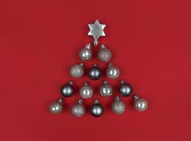 kerstboomvorm gemaakt met decorballen op een rood papier. foto
