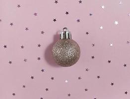 glitter kerstboom bal en confetti sterren op een roze papier. feestelijk plat leggen. foto