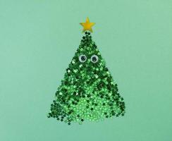 kerstboomvorm van confettisterren met ogen op een groen papier. foto