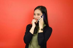 maken telefoon telefoontje en glimlachen van mooi Aziatisch vrouw geïsoleerd Aan rood achtergrond foto