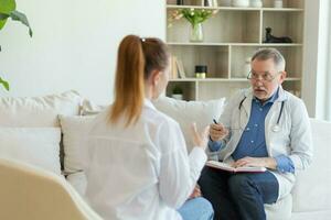 senior Mens dokter onderzoeken yound vrouw in dokter kantoor of Bij huis. meisje geduldig en dokter hebben overleg in ziekenhuis kamer. geneeskunde gezondheidszorg medisch controle. bezoek naar dokter. foto