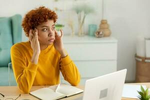 Afrikaanse vrouw aanraken tempels ervaren spanning. meisje Bij huis kantoor moe van werken gevoel hoofdpijn ziek wrijven tempels voorhoofd. lang laptop gebruik computer visie syndroom. kantoor syndroom. foto