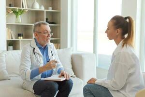 senior Mens dokter onderzoeken yound vrouw in dokter kantoor of Bij huis. meisje geduldig en dokter hebben overleg in ziekenhuis kamer. geneeskunde gezondheidszorg medisch controle. bezoek naar dokter. foto