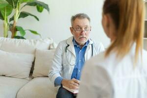 senior Mens dokter onderzoeken yound vrouw in dokter kantoor of Bij huis. meisje geduldig en dokter hebben overleg in ziekenhuis kamer. geneeskunde gezondheidszorg medisch controle. bezoek naar dokter. foto