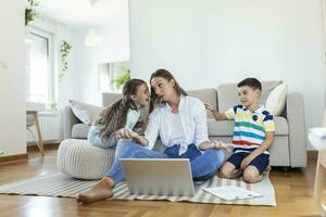 klein ondeugend kinderen lawaai maken en afleidend moeder freelancer proberen naar concentreren Aan laptop en knijpen hoofd werken Bij tafel in licht leven kamer foto