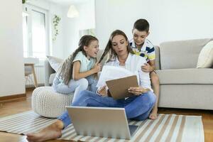 weinig ondeugend kinderen afleidend bezig jong vrouw van werk Aan laptop Bij huis foto