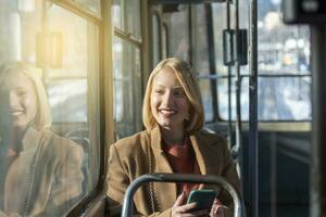 mensen in openbaar vervoer, pendelaars, vrouw passagier op zoek Bij de scherm van haar smartphone foto