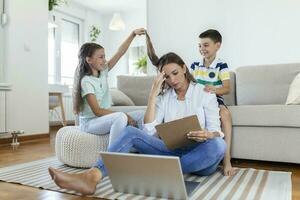 weinig ondeugend kinderen afleidend bezig jong vrouw van werk Aan laptop Bij huis foto