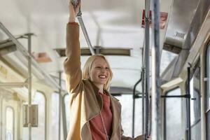 jong vrouw Holding omgaan met terwijl in beweging in de oud tram. gelukkig passagier genieten van reis Bij de openbaar vervoer foto