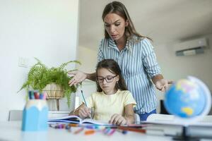 benadrukt moeder en zoon gefrustreerd over- mislukking huiswerk, school- problemen concept. verdrietig weinig meisje draaide zich om weg van moeder, doet niet willen naar Doen saai huiswerk foto