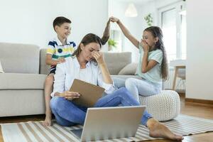 weinig ondeugend kinderen afleidend bezig jong vrouw van werk Aan laptop Bij huis foto