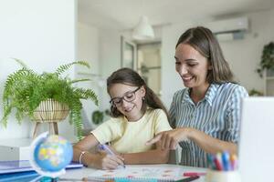 schattig meisje met moeder aan het doen huiswerk Bij huis. een moeder helpt haar weinig dochter naar Doen haar huiswerk voor de school. onderwijs en familie concept foto