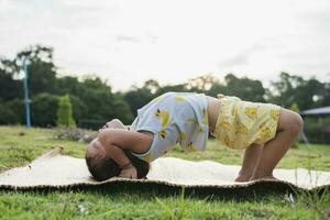 meisje aan het doen gymnastiek Aan een geschiktheid mat eenzaam Bij huis aan het doen yoga aan het doen brug natuurlijk terug buigen flexibel kinderen aan het doen gymnastiek- opdrachten. sport, aan het leren, fitheid, uitrekken, actief levensstijl concept. foto