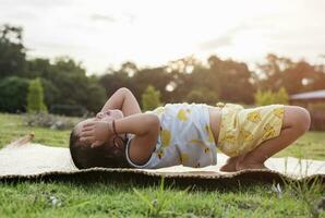 meisje aan het doen gymnastiek Aan een geschiktheid mat eenzaam Bij huis aan het doen yoga aan het doen brug natuurlijk terug buigen flexibel kinderen aan het doen gymnastiek- opdrachten. sport, aan het leren, fitheid, uitrekken, actief levensstijl concept. foto