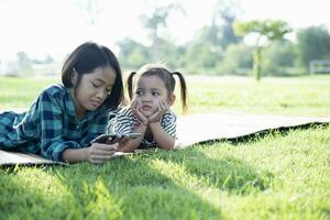 zuidoosten Aziatisch meisjes Speel mobiel telefoons buitenshuis in de binnenplaats gedurende de zomer Aan vakantie. foto