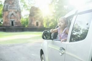 gelukkig meisje in haar auto bereiken buiten de auto, gevoel de vers lucht en warm zonneschijn gedurende een reis. foto