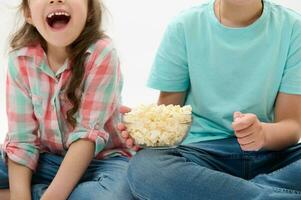 details Aan een kom van popcorn in de handen van schattig kinderen aan het kijken films of tekenfilms over- wit geïsoleerd achtergrond foto