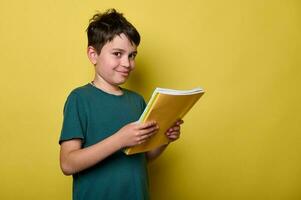 knap tiener- jongen glimlachen op zoek Bij camera, Holding studieboeken, klaar naar begin een nieuw semester van academisch school- jaar foto