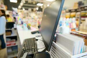 gedeeltelijk visie van een valuta balie, Notitie tellen machine en pc toezicht houden op Aan de ontvangst bureau in school- schrijfbehoeften winkel foto