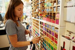 charmant vrouw verkoper stonk kleur potloden in schappen in kunst creatief op te slaan. kantoor levering en school- schrijfbehoeften winkel foto