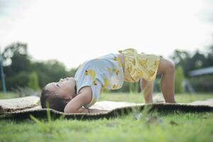 meisje aan het doen gymnastiek Aan een geschiktheid mat eenzaam Bij huis aan het doen yoga aan het doen brug natuurlijk terug buigen flexibel kinderen aan het doen gymnastiek- opdrachten. sport, aan het leren, fitheid, uitrekken, actief levensstijl concept. foto