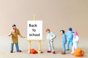 leraar en studenten in de buurt van canvas op ezel met het woord terug naar school foto