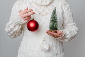 vrouw houdt een kerstboom en een ornament vast foto