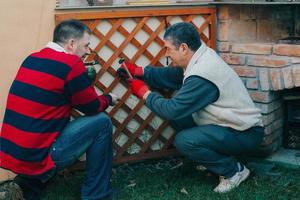jonge volwassen volwassene helpt senior man met tuinieren