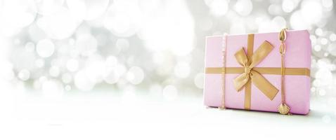 roze geschenkdoos met gouden lint en gouden versieringen met bokeh achtergrond en kopieer ruimte foto