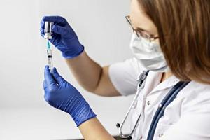 een vrouwelijke arts die een medisch masker draagt, trekt het coronavirusvaccin in een spuit in de kliniek. Het concept van vaccinatie, immunisatie, preventie tegen covid-19.