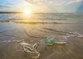 afval de strandzee plastic fles ligt op het strand en vervuilt de zee en het leven van het zeeleven gemorst afval op het strand van de grote stad. lege gebruikte vuile plastic flessen