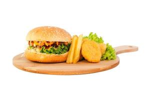 Kip hamburger met nuggets en frietjes op een houten plaat op witte achtergrond foto